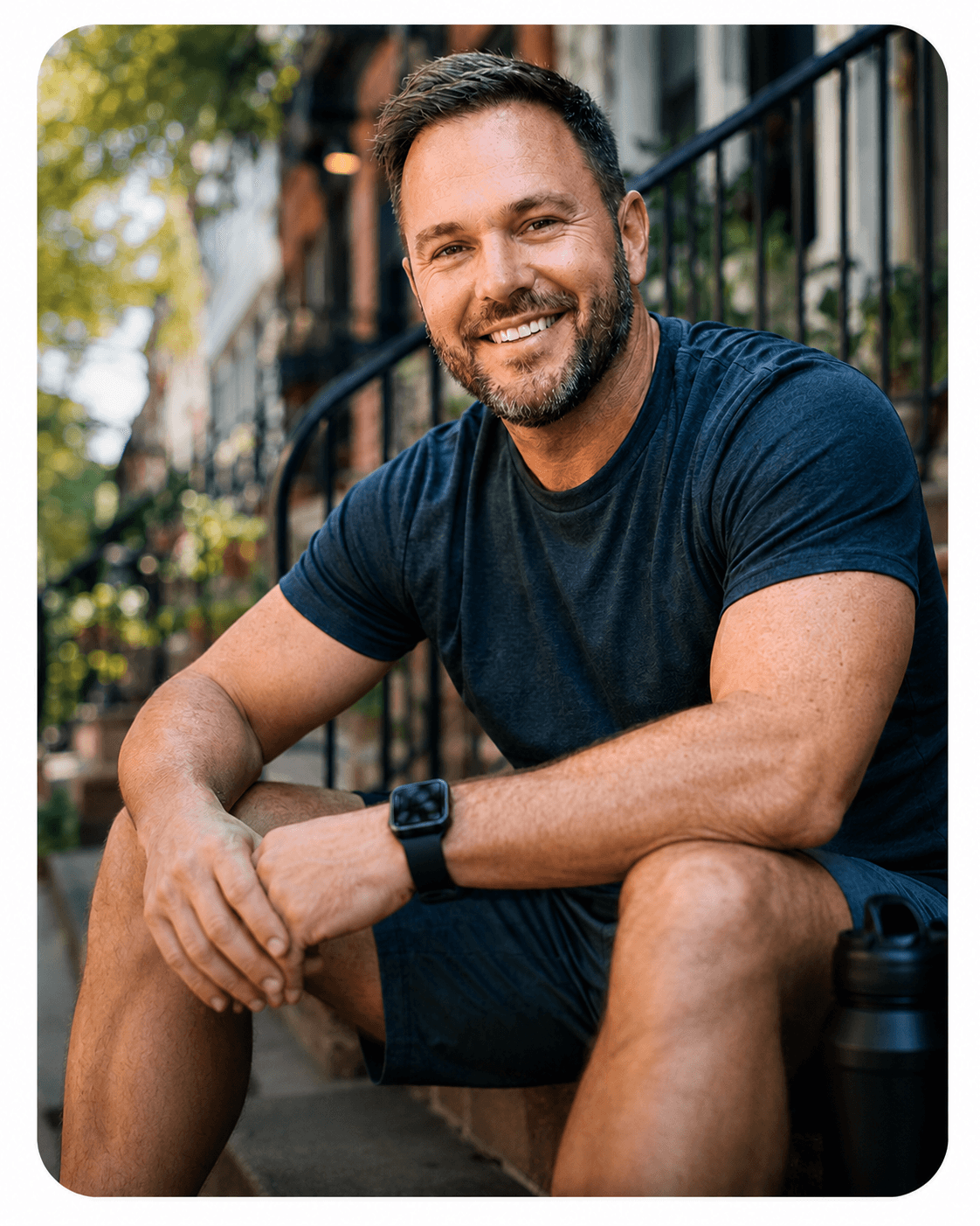 A smiling man sitting on outdoor steps